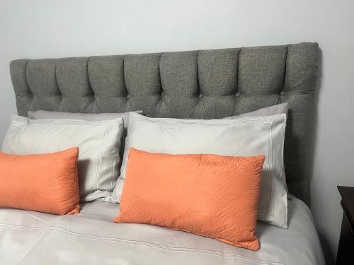 a bed with an orange pillow and white pillows at Oryx guest house in Oakdale