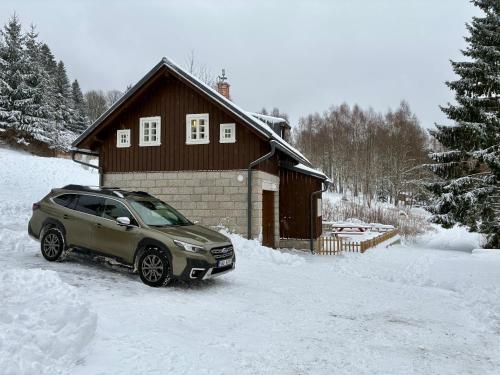 a car parked in the snow in front of a house at Chalupa Andělka in Josefŭv Dŭl