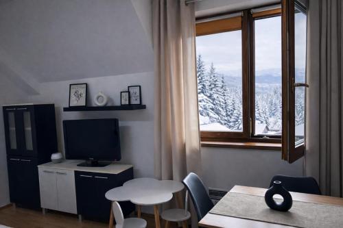 un soggiorno con un tavolo e una finestra con vista di Kamzík Ski Apartment Donovaly - Apartmán 64 hneď pri zjazdovke a Donovaly