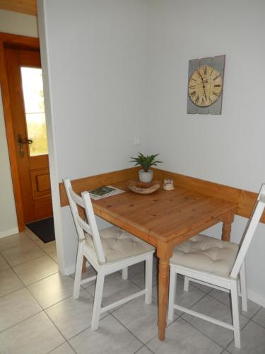 a wooden table with two chairs and a clock on the wall at Haus am Wald in Steindorf am Ossiacher See