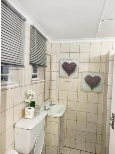 a bathroom with a toilet and a sink and hearts on the wall at 37 on Bell self catering accommodation in Harrismith