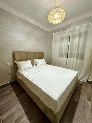 una camera da letto con un grande letto bianco con un lampadario di Monopolio gar tgv 5 min a Tangeri