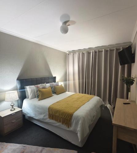 a bedroom with a large bed with curtains and a desk at 37 on Bell self catering accommodation in Harrismith