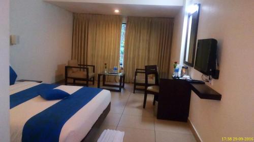 a hotel room with a bed and a television at Clouds Valley Hotel in Munnar