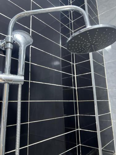 doccia con piastrelle nere e soffione di Residence Ndeye Ngouye a Dakar