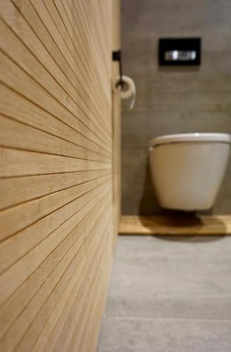 a wooden door in a bathroom with a toilet at FjordView Sanctuary in Nedstrand