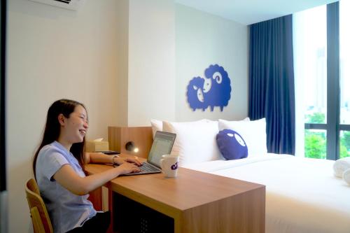 una donna seduta a una scrivania con un computer portatile in una stanza d'albergo di Kokotel Cebu Adira a Cebu City