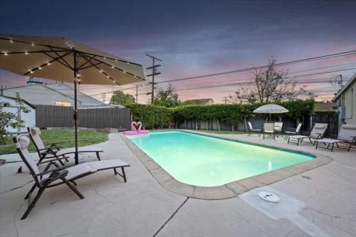 a swimming pool with chairs and an umbrella at Chic Boho Retreat - Pool, Spa, Patio, Mini Golf & Arcade, Mins from Universal Studios! in Los Angeles