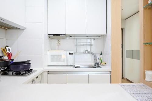 a white kitchen with a sink and a microwave at Gangnam Opal in Seoul