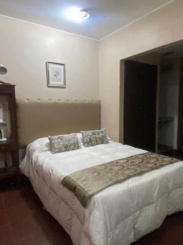 een slaapkamer met een groot wit bed met twee kussens bij Hotel Casa del Peregrino in Salta