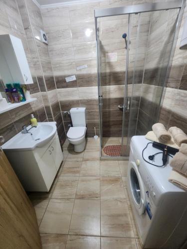 a bathroom with a shower and a washing machine at Vaikiki Apartman LM in Novi Pazar