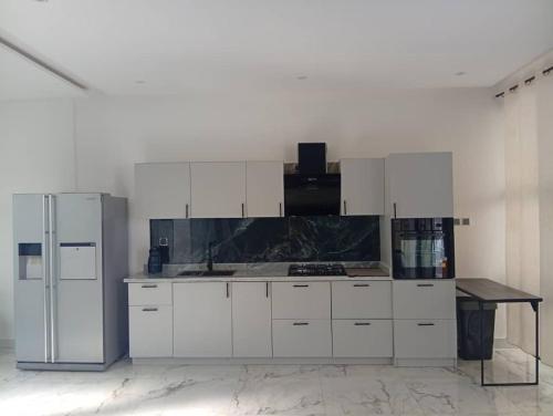 una cucina con mobili bianchi e un frigorifero di Villa Blanche a Cotonou