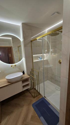 a bathroom with a sink and a shower with a mirror at Delux Apartament z jacuzzi in Pszczyna