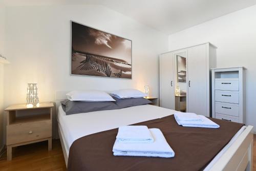 een slaapkamer met een groot bed met twee handdoeken erop bij EnVi Apartments in Murter