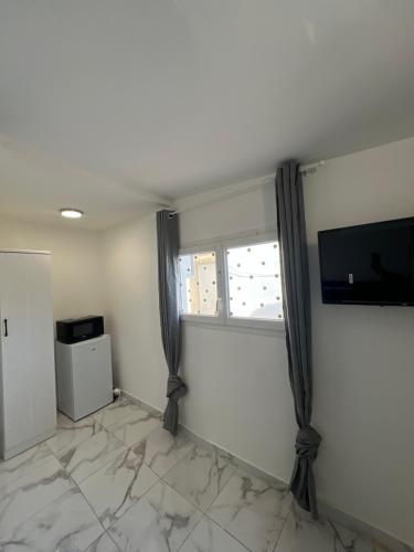 un salon avec une télévision et une fenêtre dans l'établissement Casa Bianca, à Marseille