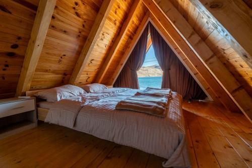 a bed in a wooden room with a large window at Apartmani Janjusevic in Nikšić