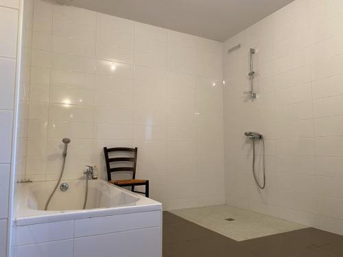 a white bathroom with a tub and a chair at Maison familiale in Vars
