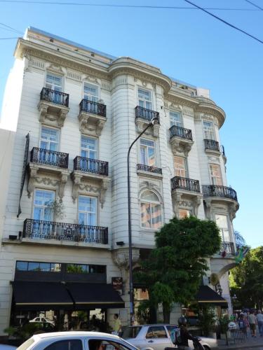 a large white building with balconies on a street at Hotel Benevento in La Plata