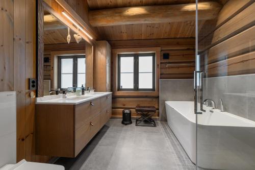 een badkamer met twee wastafels, een bad en een douche bij Nordic Gateway Logde in Hafjell