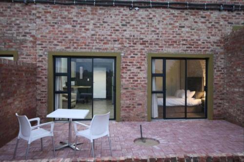 een patio met een tafel en stoelen en een slaapkamer bij Sunrise Serenity Estate in Potchefstroom