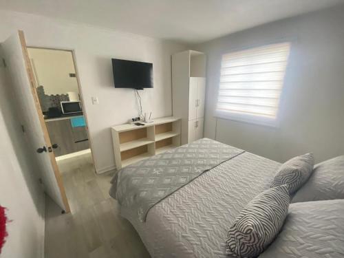 a bedroom with a bed and a television and a window at casa reñaca sector jardín del mar in Viña del Mar