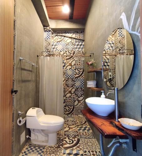 a bathroom with a toilet and a sink and a mirror at HELEN HOUSE Bello Horizonte in Santa Marta