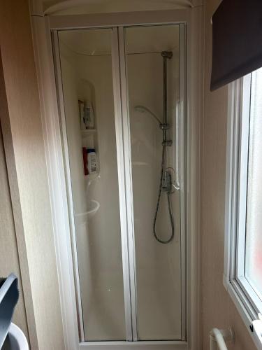a shower in a bathroom next to a window at BZ Green Haven Caravan in Ballantrae