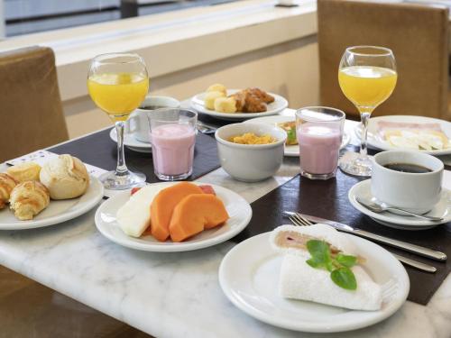 une table avec des assiettes de nourriture et des verres de vin dans l'établissement Mercure Sao Paulo Grand Plaza Paulista, à São Paulo