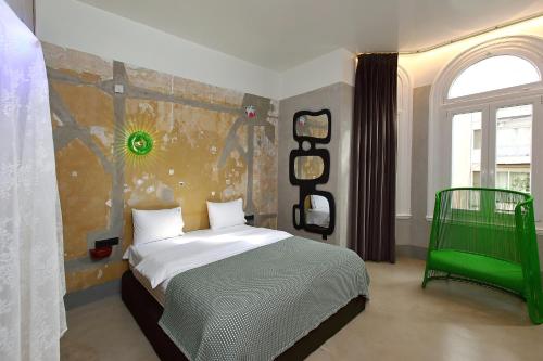 a bedroom with a bed and a green chair at Paradox in Thessaloniki