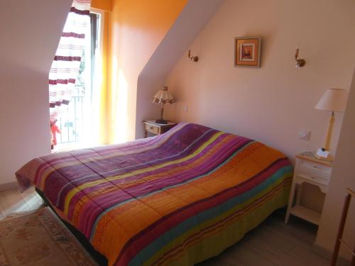 een slaapkamer met een bed met een kleurrijk gestreepte deken bij Villa Lou Ann in Pontchâteau