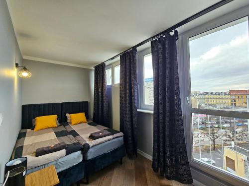 a bedroom with a bed and a large window at AM apartments 6 Szczecin City Center Wyzwolenia in Szczecin