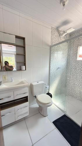 a white bathroom with a toilet and a shower at Bruna in Florianópolis