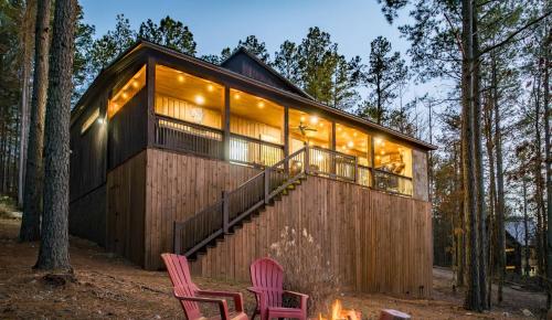 a cabin in the woods with two chairs and a fire at Serene mountain cabin with hot tub and 2 ensuites in Stephens Gap