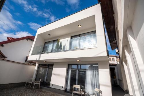 a white house with chairs in front of it at Felicita Deluxe Apartments with Free Parking in Sarajevo
