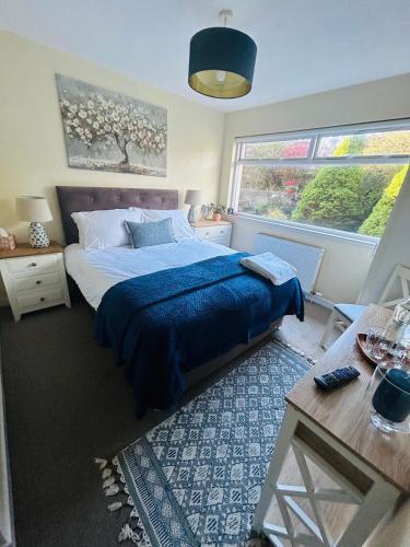 a bedroom with a bed and a table and two windows at Four Seasons B&B, Ground floor room, private bathroom, 3rd floor loft living area & self serve continental breakfast in Pitlochry