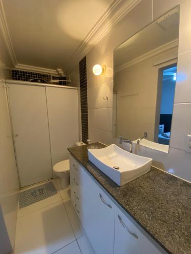 een badkamer met een wastafel, een toilet en een spiegel bij Suíte Aconchegante in Belém