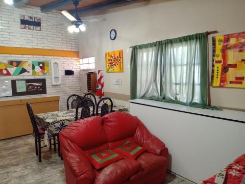 un soggiorno con una sedia rossa e un tavolo di Malargue Style a 100 MTS del Centro a Malargüe