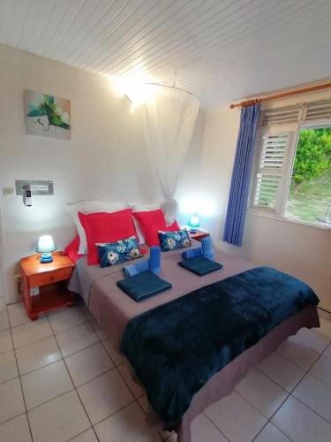 a bedroom with a large bed with red pillows at Les Orchidées - classé 3 étoiles -Plage à 5 mn in Sainte-Anne