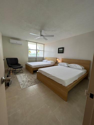 a bedroom with two beds and a chair in it at Island bliss apartment in Fajardo