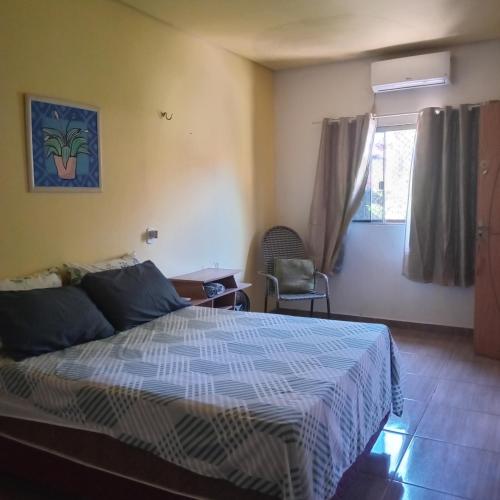 a bedroom with a bed and a chair and a window at Carolina com Ká in Carolina