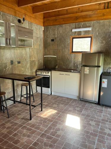 een keuken met een tafel en een koelkast bij cabañas walls 3 in Pucón