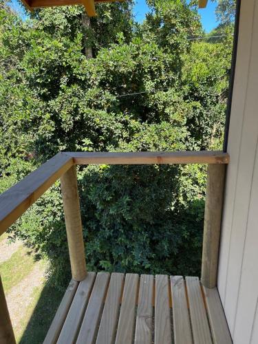 een veranda met een houten terras met bomen op de achtergrond bij cabañas walls 3 in Pucón