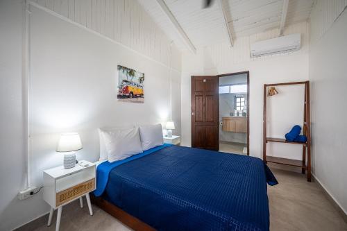 a bedroom with a blue bed in a white room at Ozeano Hotel & Surf Bar in Jacó