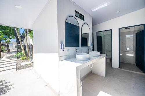 a white bathroom with two sinks and a mirror at Ozeano Hotel & Surf Bar in Jacó