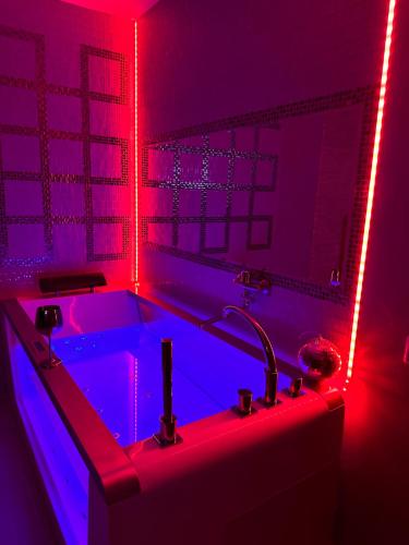 een badkamer met een badkuip met blauwe en rode lampen bij Jacuzzi studios 777 in Palanga
