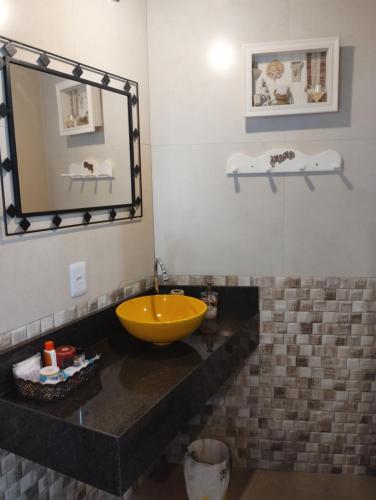 a bathroom with a yellow sink and a mirror at Studio Gamboa in Garopaba