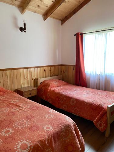 a room with two beds and a window with a curtain at cabañas walls 2 in Pucón