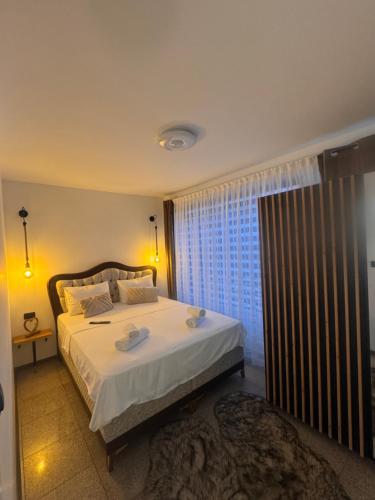 ein Schlafzimmer mit einem Bett mit weißer Bettwäsche und einem Fenster in der Unterkunft Apartman Booem in Bihać