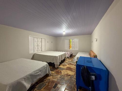 a room with two beds and a blue table in it at Casa aconchegante e tranquila in Chapada dos Guimarães