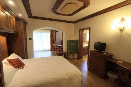 a bedroom with a bed and a television in it at Dolasilla Park Hotel in Vigo di Fassa